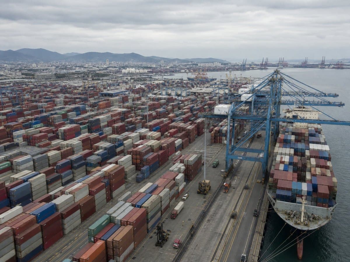 An aerial view of a busy shipping port with stacked cargo containers and a cargo ship.