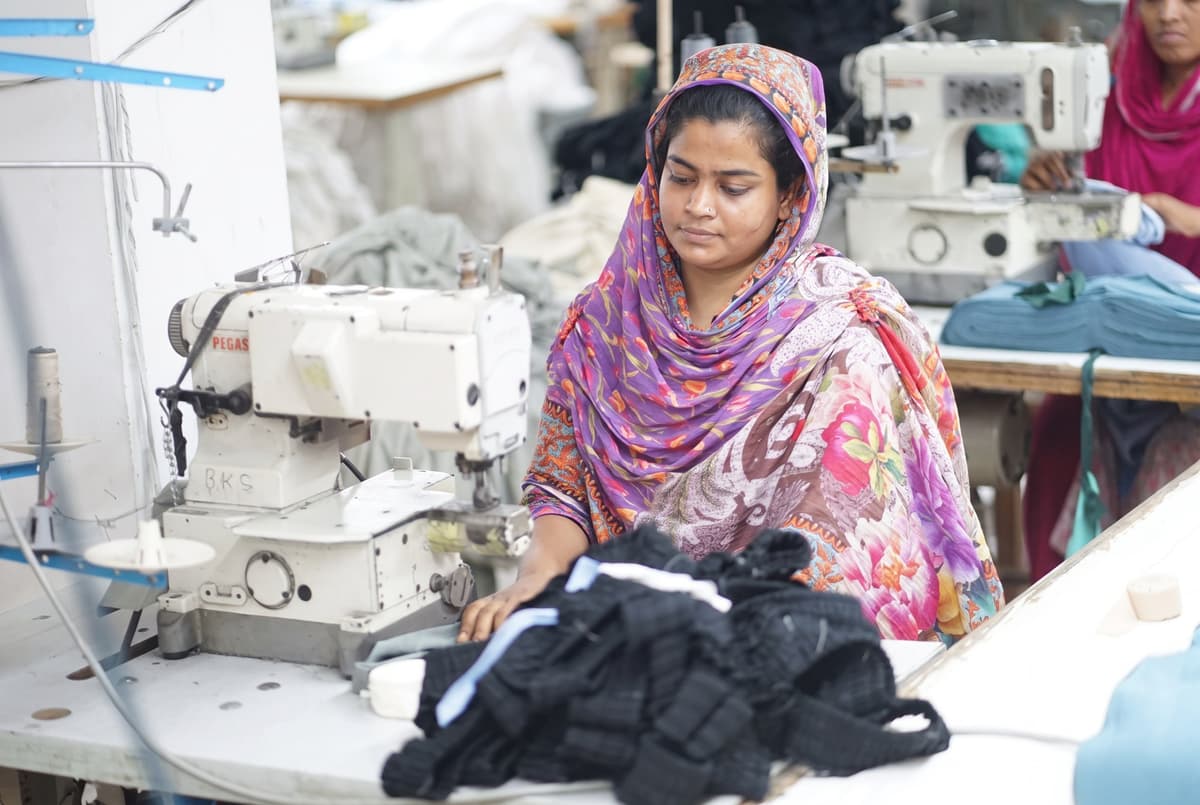Moushumi at her sewing station at Collective Studio, surrounded by garment pieces.