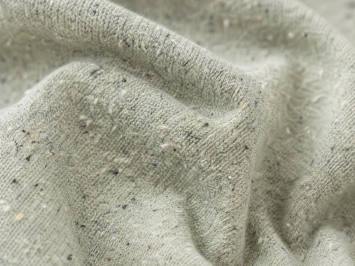 Close-up of recycled cotton-blend knit fabric with a fleck texture.
