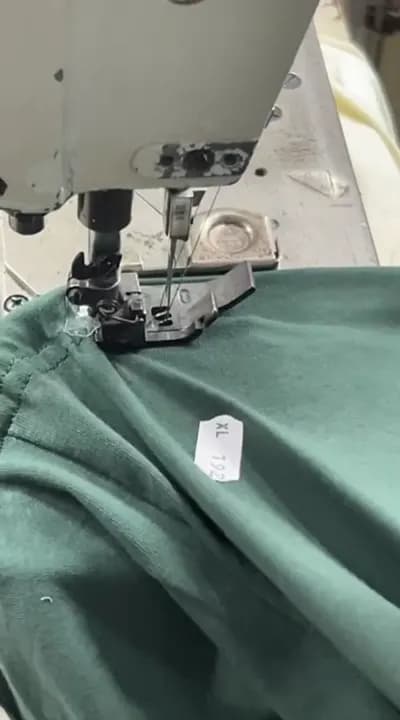 A green single jersey t-shirt under an industrial sewing machine at Collective Studio in Narayanganj.